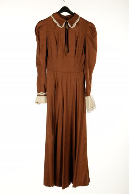 Barna műszálas ruha és fehér madeirás melleskötény